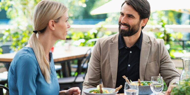 Happy couple sitting outdoors on terrace restaurant, talking